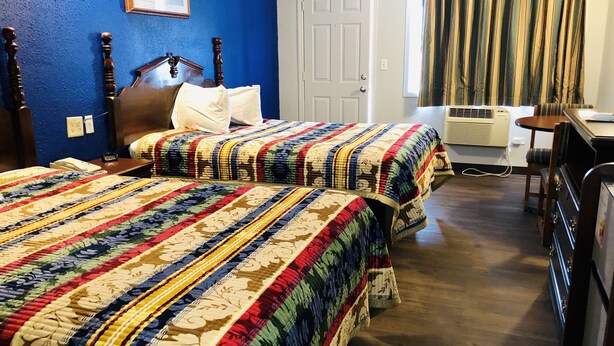 Habitación de hotel con dos camas, un escritorio y un aire acondicionado.