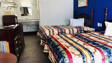 A hotel room with two beds, a desk, a dresser, and a bathroom visible through an open door.