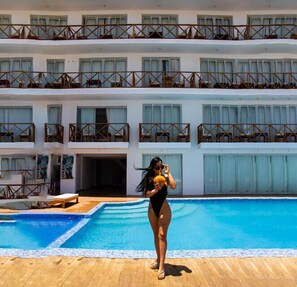 Un hôtel à plusieurs étages doté de balcons, d’une piscine et d’une terrasse couverte.