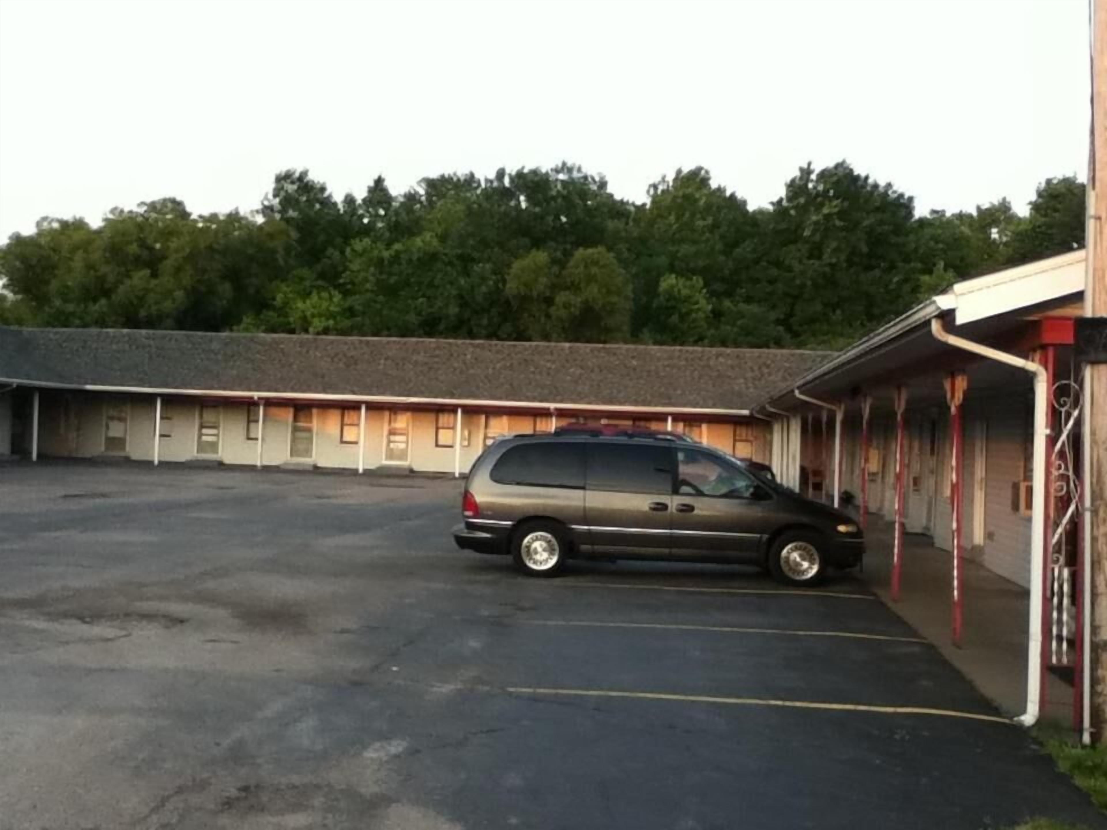 A motel with a parking lot and a van parked in front.