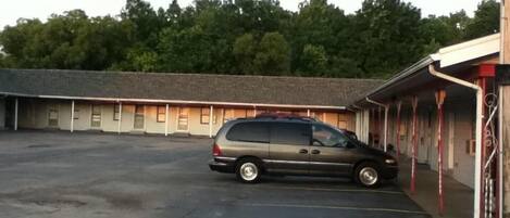A motel with a parking lot and a van parked in front.