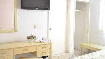 Un dormitorio con cama, mesita de noche, cómoda, televisor y armario.