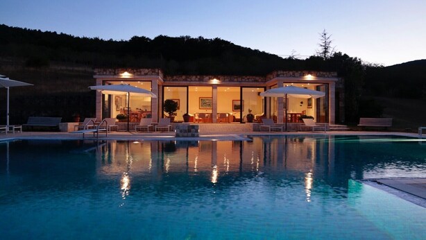 Una casa moderna con piscina, mobiliario de exterior y zona de comedor.