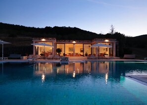 Una casa moderna con piscina, mobiliario de exterior y zona de comedor.