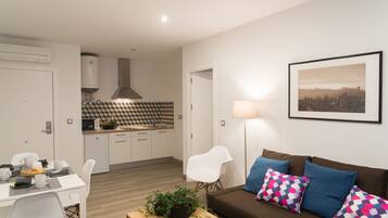 A modern living space with a dining area, kitchenette, and a sofa with patterned cushions.