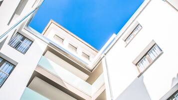 Un edificio moderno con varios balcones y un cielo azul despejado visible a través de las ventanas.