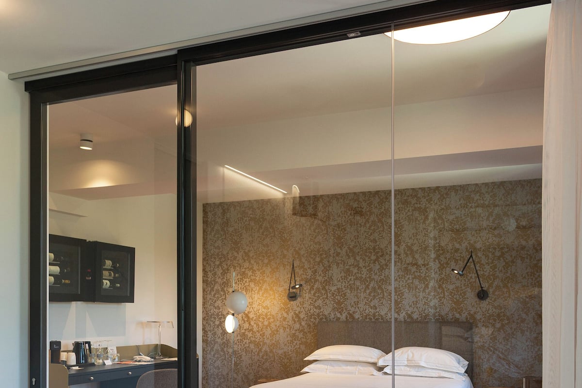Et moderne hotelværelse med et stort badekar, en seng med hvide sengetøj, et skrivebord med stol og et lille bord med lampe.