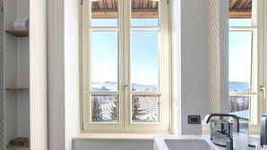Un baño moderno con un ventanal grande, un lavabo de mármol y un taburete pequeño.