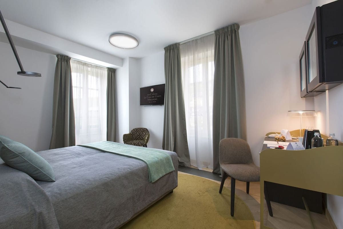 Et hotelværelse med seng, skrivebord, stol og fjernsyn.