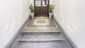 Una imponente escalera que conduce a una puerta con una lámpara decorativa en el techo.