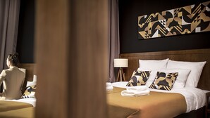 Una habitación de hotel con una cama, almohadas, una lámpara y una obra de arte en la pared.