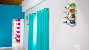 A hallway with teal curtains, a wall-mounted wine rack, and a door with red and white curtains. - Casa Tamar Guest Apartments (Kingston)