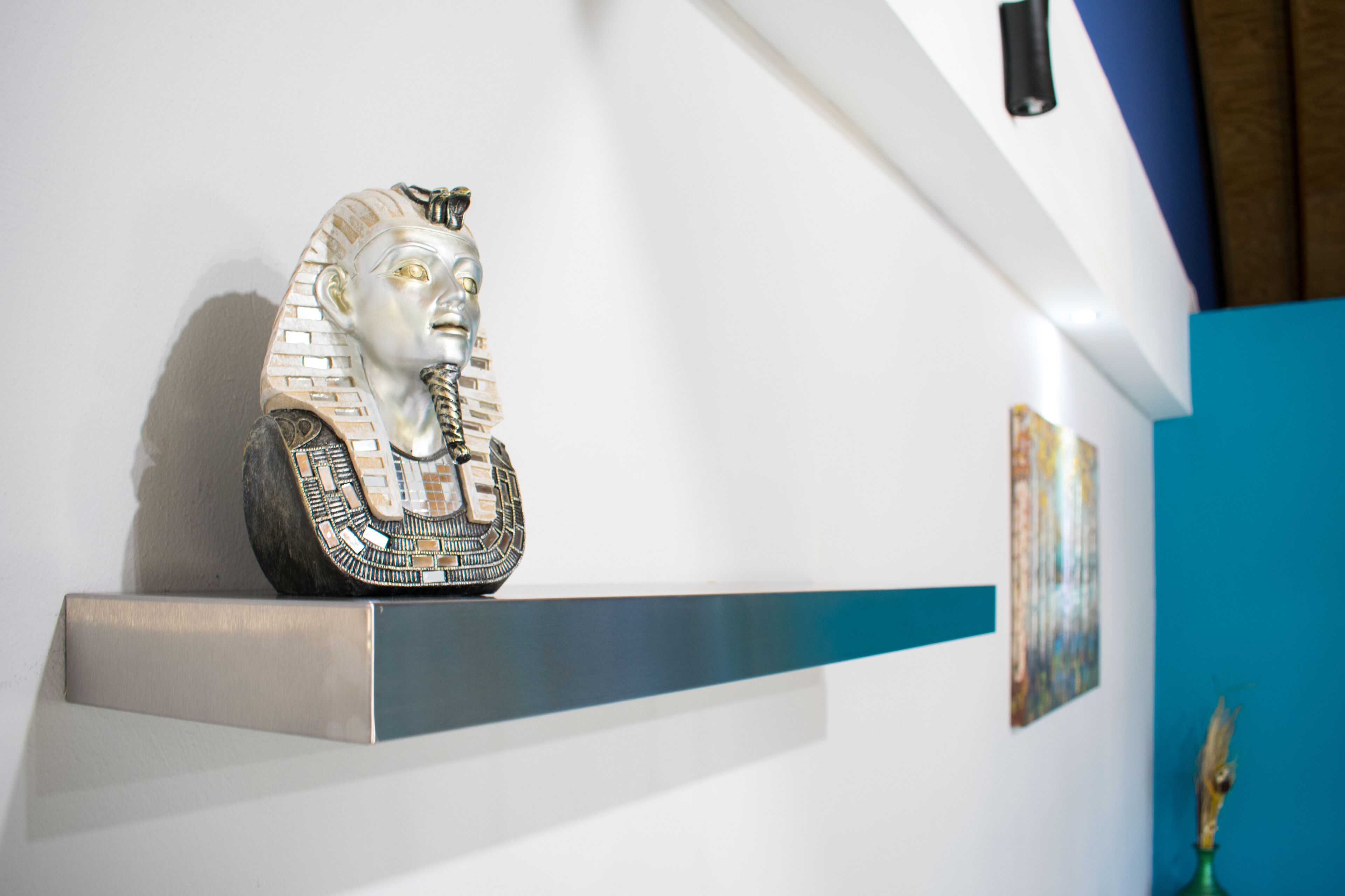A bust of a historical figure on a shelf against a wall.