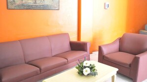 A room with a brown sofa, a brown armchair, and a small table with a flower arrangement.