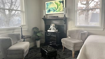 Ein Wohnzimmer mit Kamin, zwei Sesseln, einem Couchtisch und einem Gemälde an der Wand.