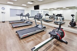 Un centre de remise en forme équipé de plusieurs tapis de course, de vélos d’appartement et d’un appareil d’aviron.