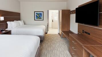 A hotel room with two beds, a flat-screen TV, a wooden wardrobe, and a carpeted floor.
