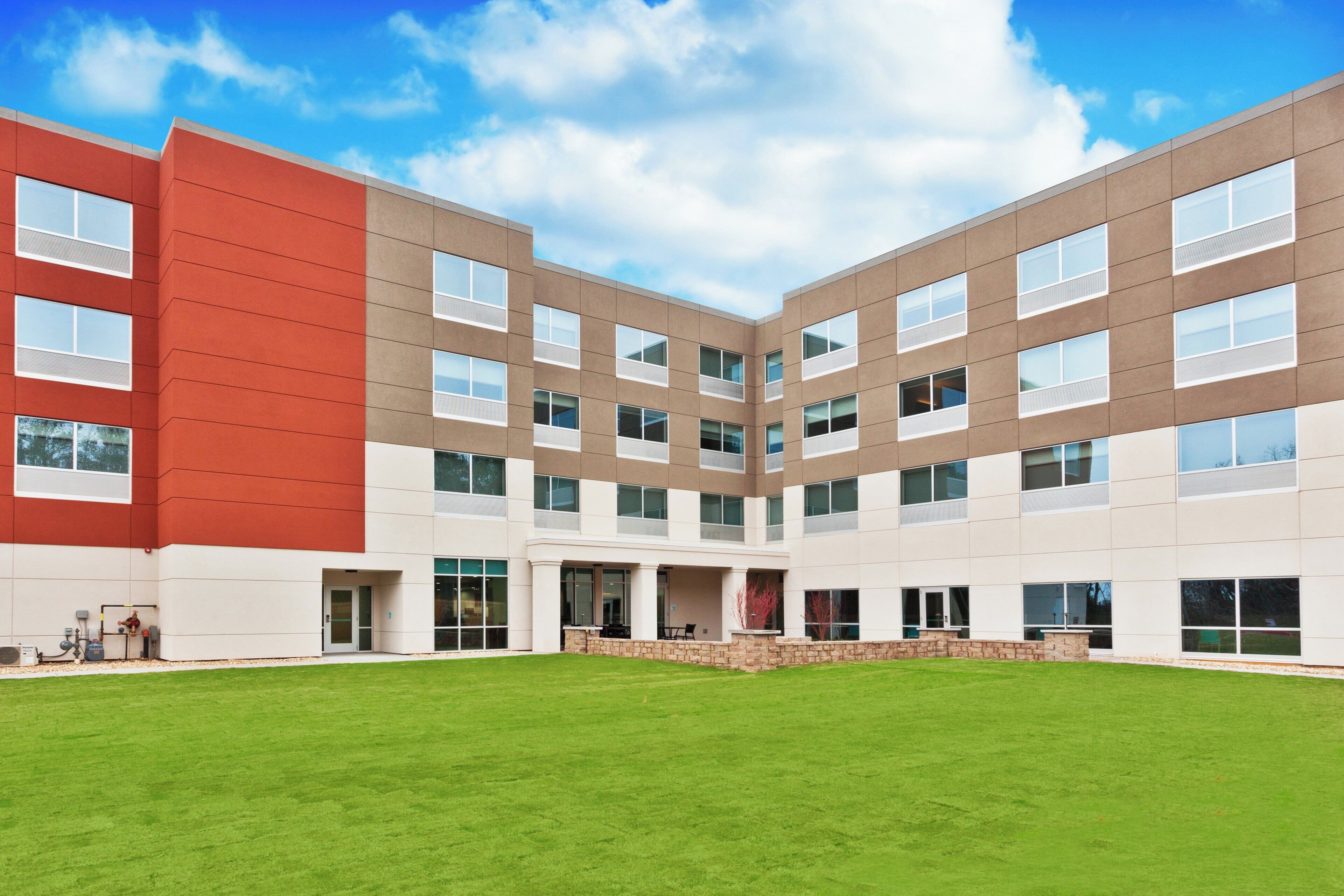 A modern building with a flat roof, large windows, and a central courtyard with a well-maintained lawn.
