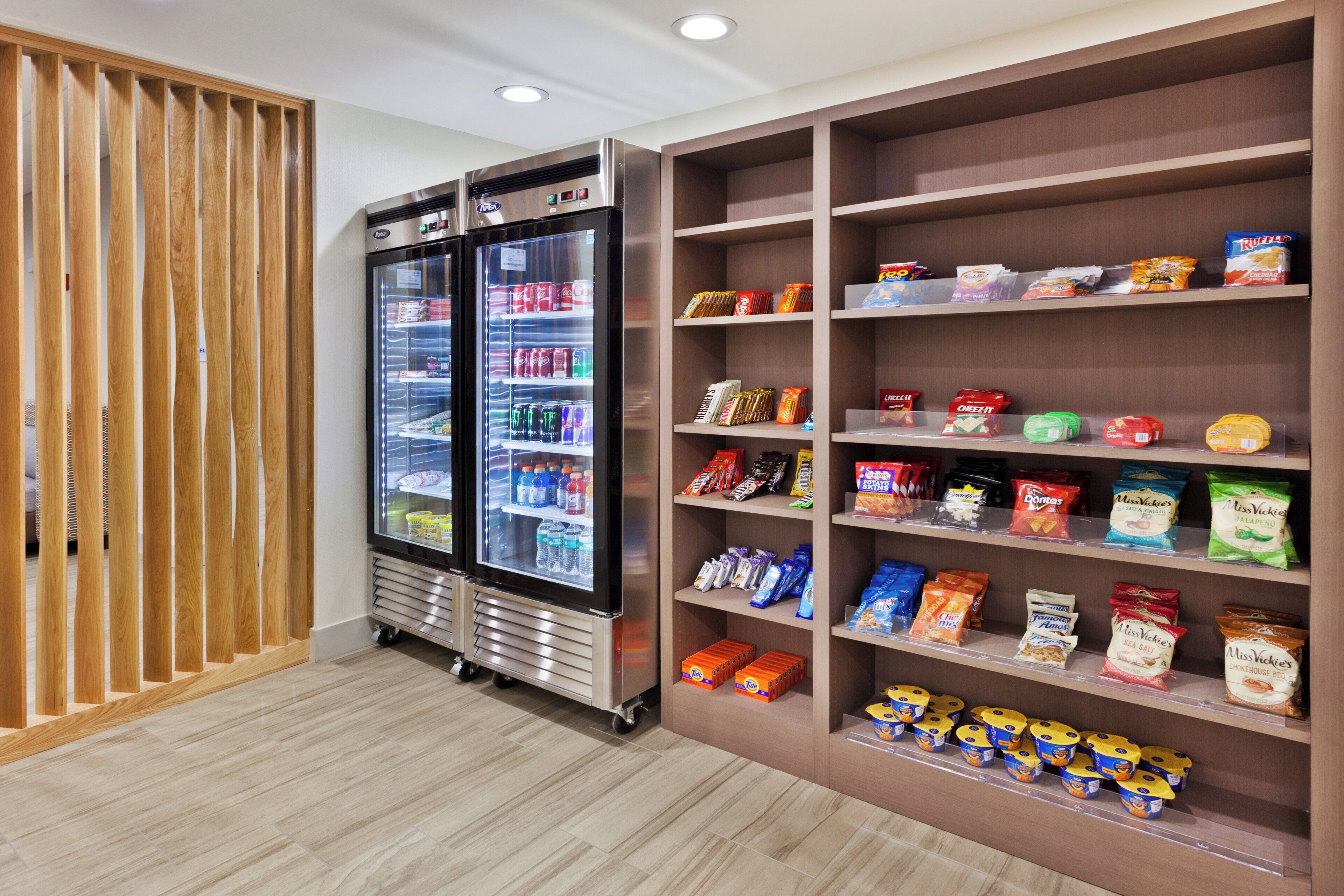A snack and beverage vending area with a refrigerator and shelves stocked with various snacks and drinks.