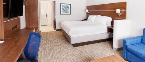 Quarto de hotel com cama, escrivaninha, cadeira, televisão e sofá azul.