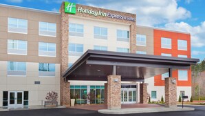 Un bâtiment de l’hôtel Holiday Inn Express & Suites doté d’une entrée abritée, de nombreuses fenêtres et d’une façade en pierre.
