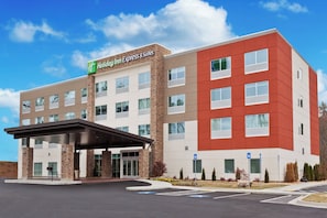 Un hotel Holiday Inn Express & Suites con un diseño moderno, que cuenta con una entrada cubierta y un estacionamiento.