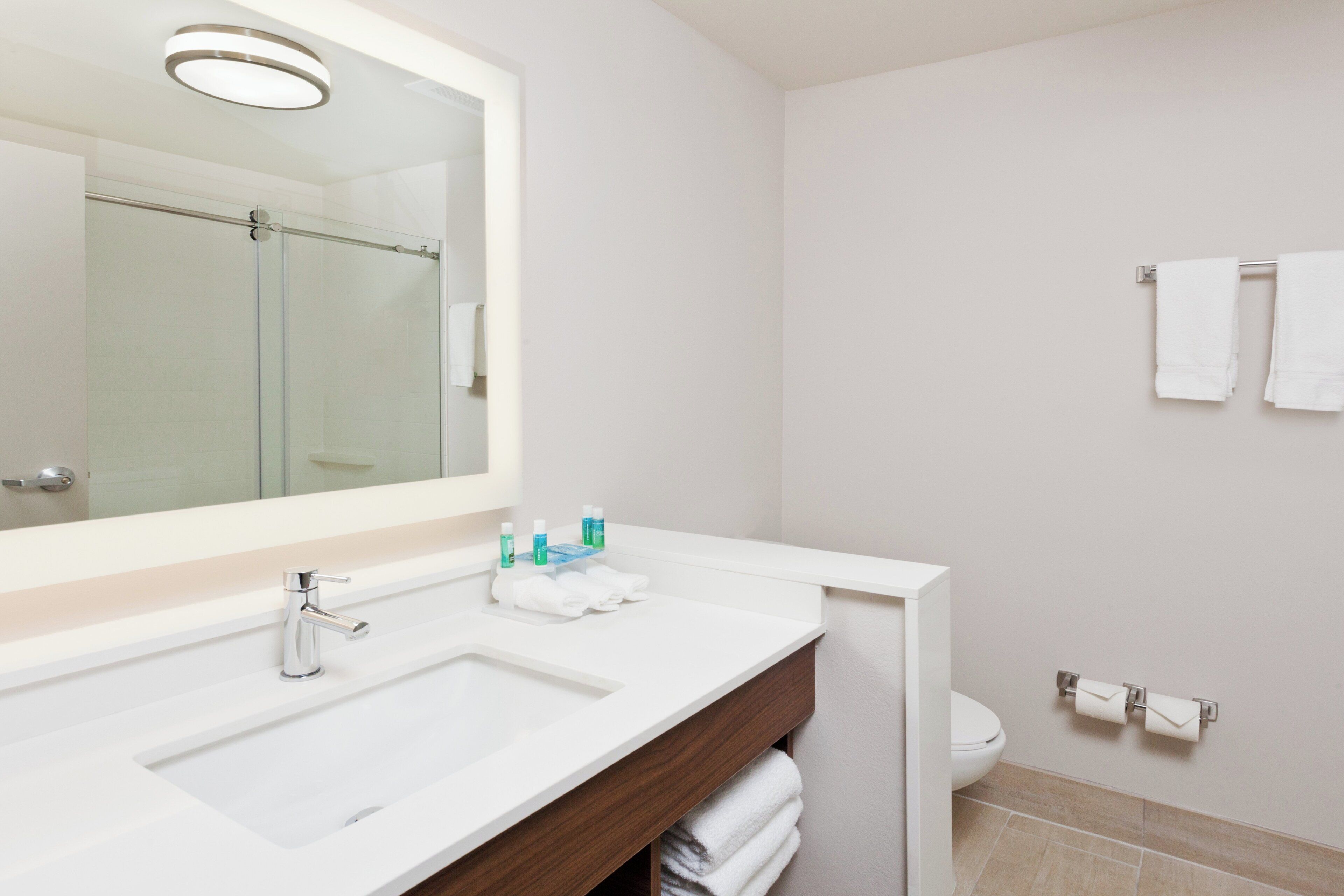 Un baño moderno con un espejo grande, un lavabo blanco y un inodoro.