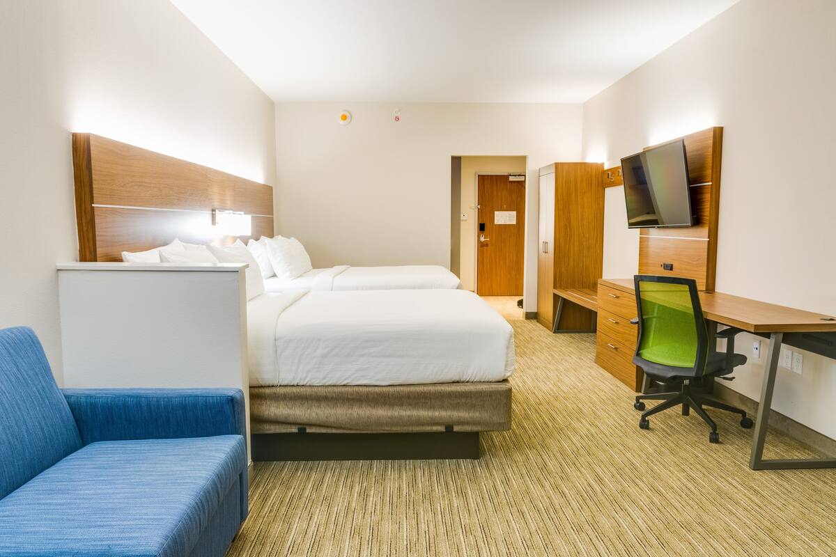 Una camera d'albergo con un letto, una scrivania, una sedia, una televisione e un armadio.