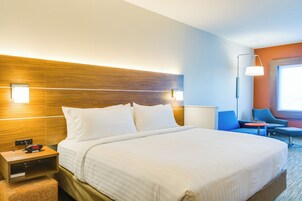 Habitación de hotel con una cama grande, mesitas de noche, un escritorio, una silla y una lámpara.