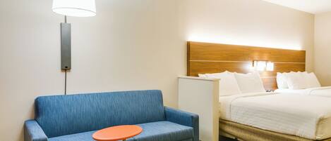 Ein Hotelzimmer mit einem Bett, einem blauen Sofa, einem kleinen Tisch und einer Wandlampe.