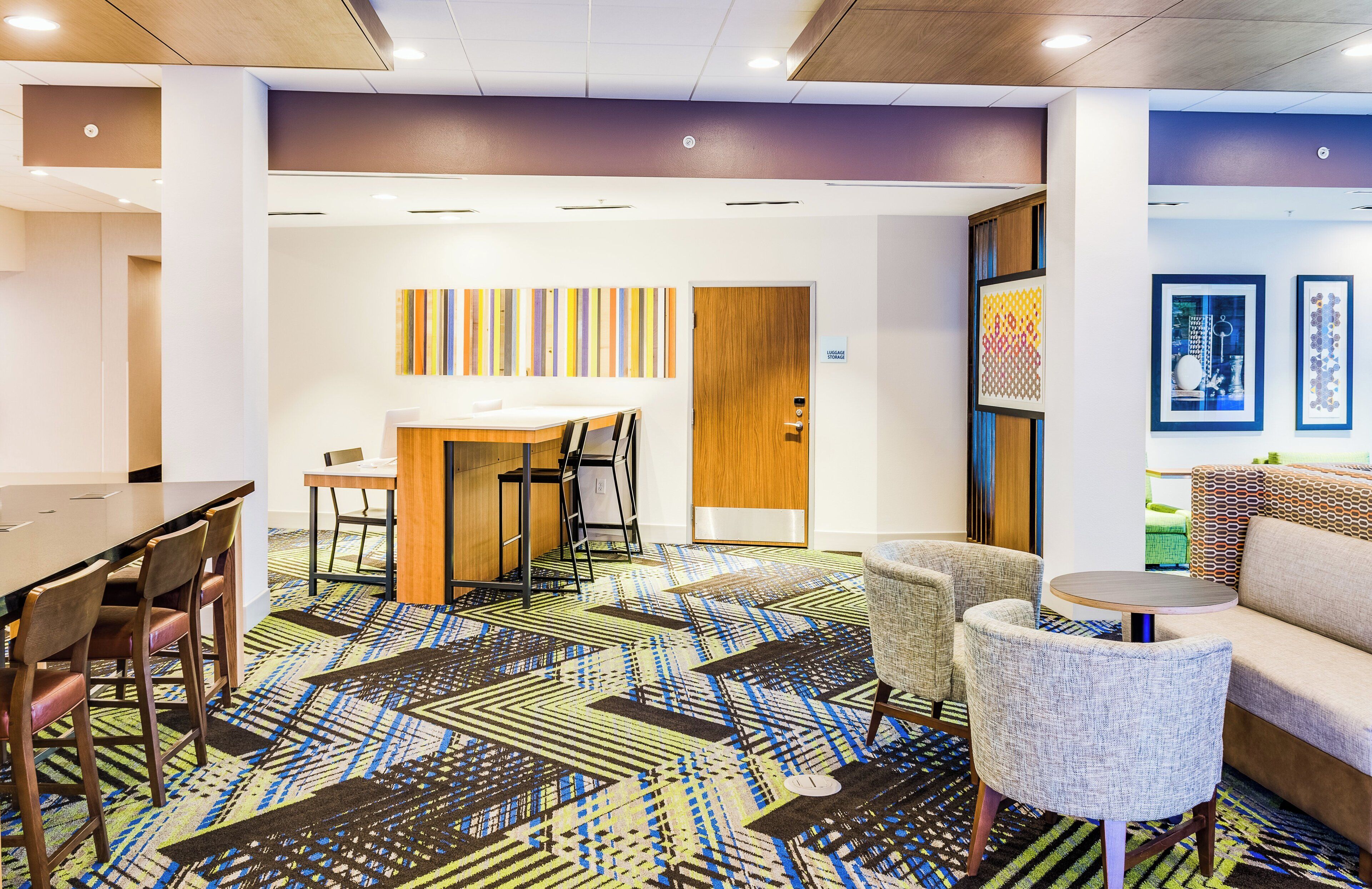 A modern hotel lobby with a dining area, seating, and artwork.