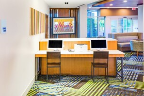 Un espacio de trabajo con dos escritorios, cada uno con un monitor de computadora, una impresora y una silla.