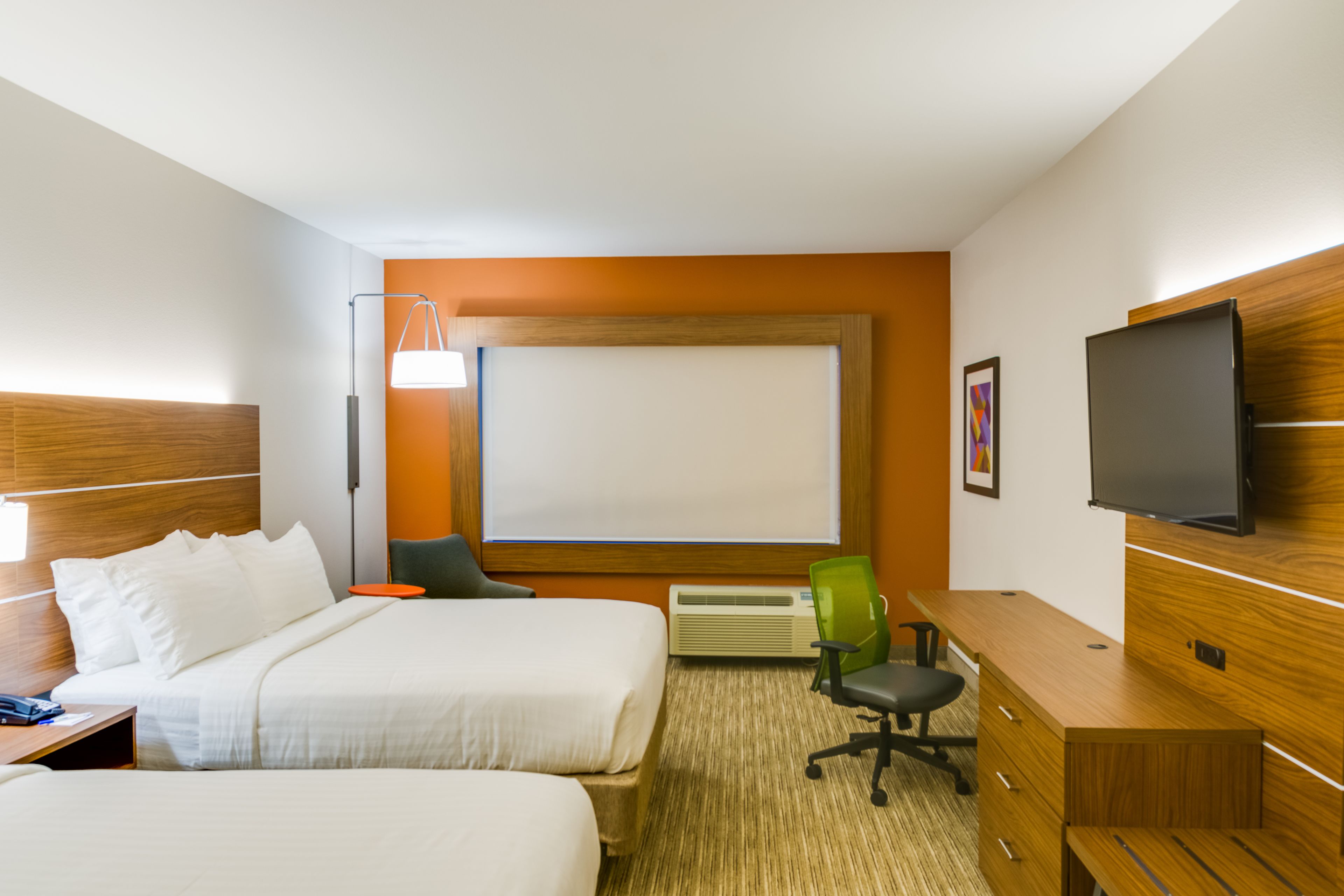 A hotel room with two beds, a desk, a chair, a television, and a large window.
