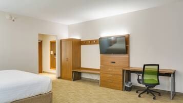 Een hotelkamer met een bed, een bureau met stoel, een televisie en een kledingkast.