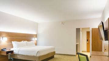 Una habitación de hotel con una cama, mesita de noche, lámpara y televisor.