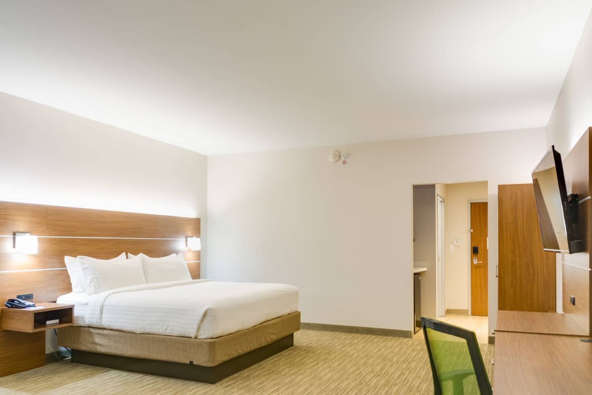 Una camera d'albergo con un letto, un comodino, una TV e una porta che dà su un bagno.