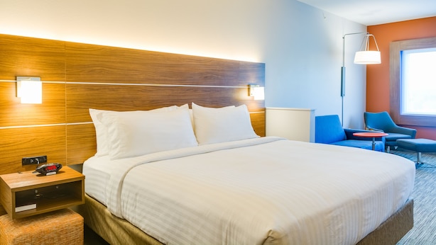 Ein Hotelzimmer mit einem großen Bett, Nachttischen, einem Schreibtisch und einem Stuhl.