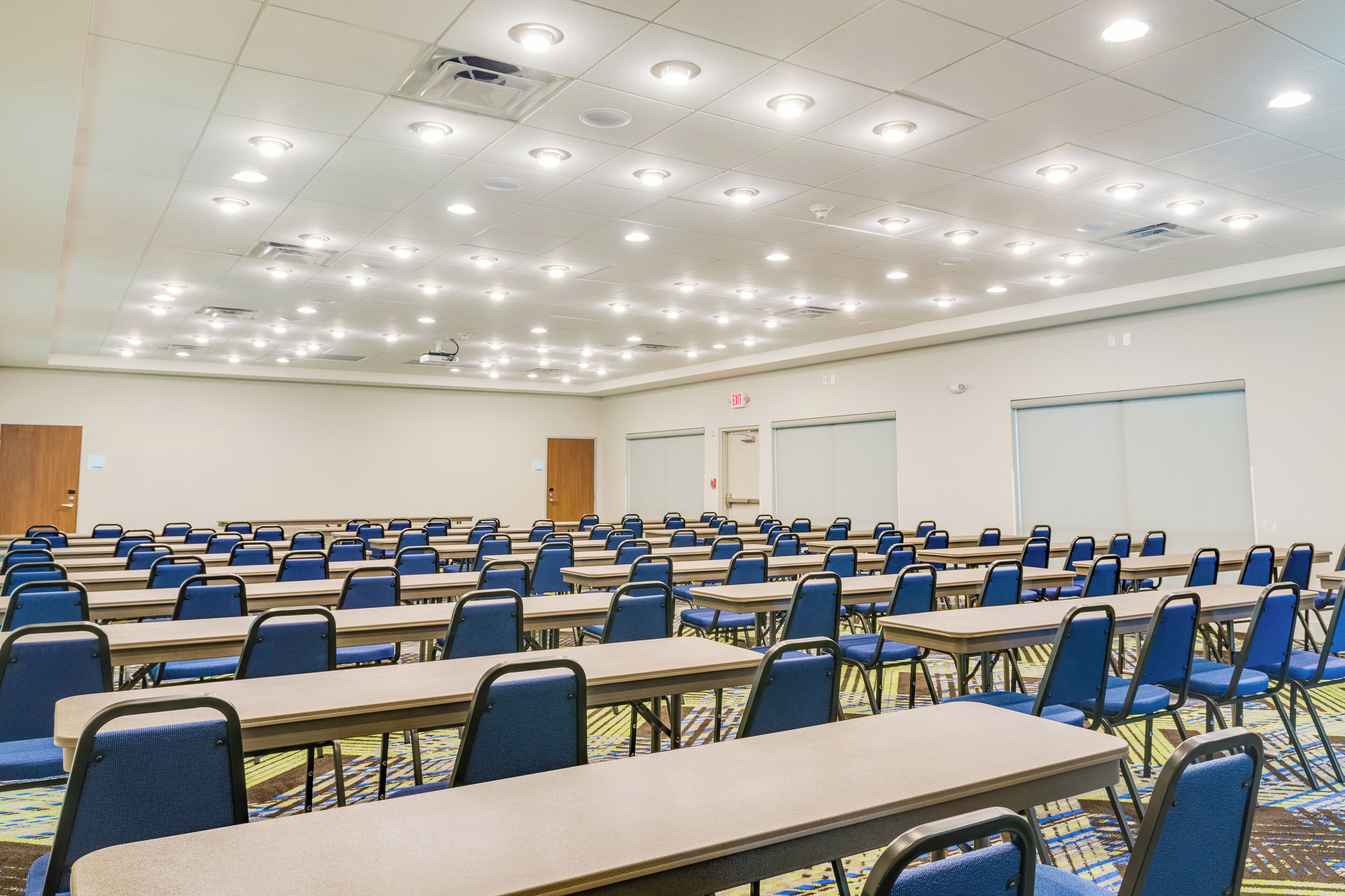 A conference room with rows of tables and chairs, a whiteboard, and a projector.