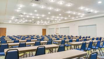 A conference room with rows of tables and chairs, a whiteboard, and a projector.