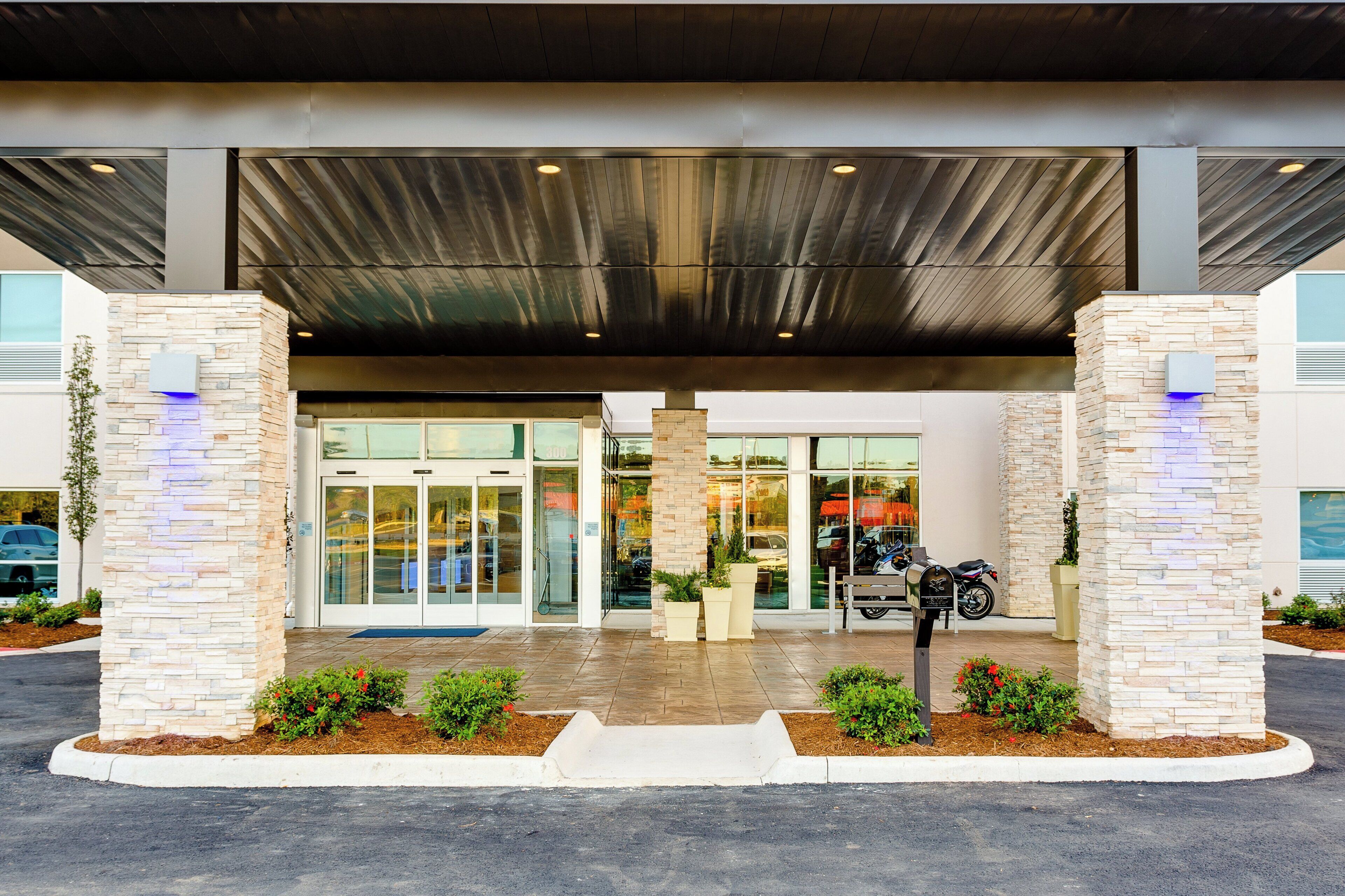 A building entrance with a covered walkway, glass doors, and a mailbox.