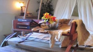 Una mesa de madera rústica con un banco, un escritorio pequeño con una lámpara y una cama con dosel.