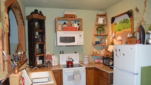 Una cocina con armarios de madera, una estufa blanca, un microondas y un refrigerador.