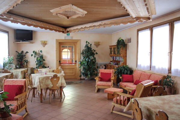 A cozy room with wooden furniture, a television, and large windows.