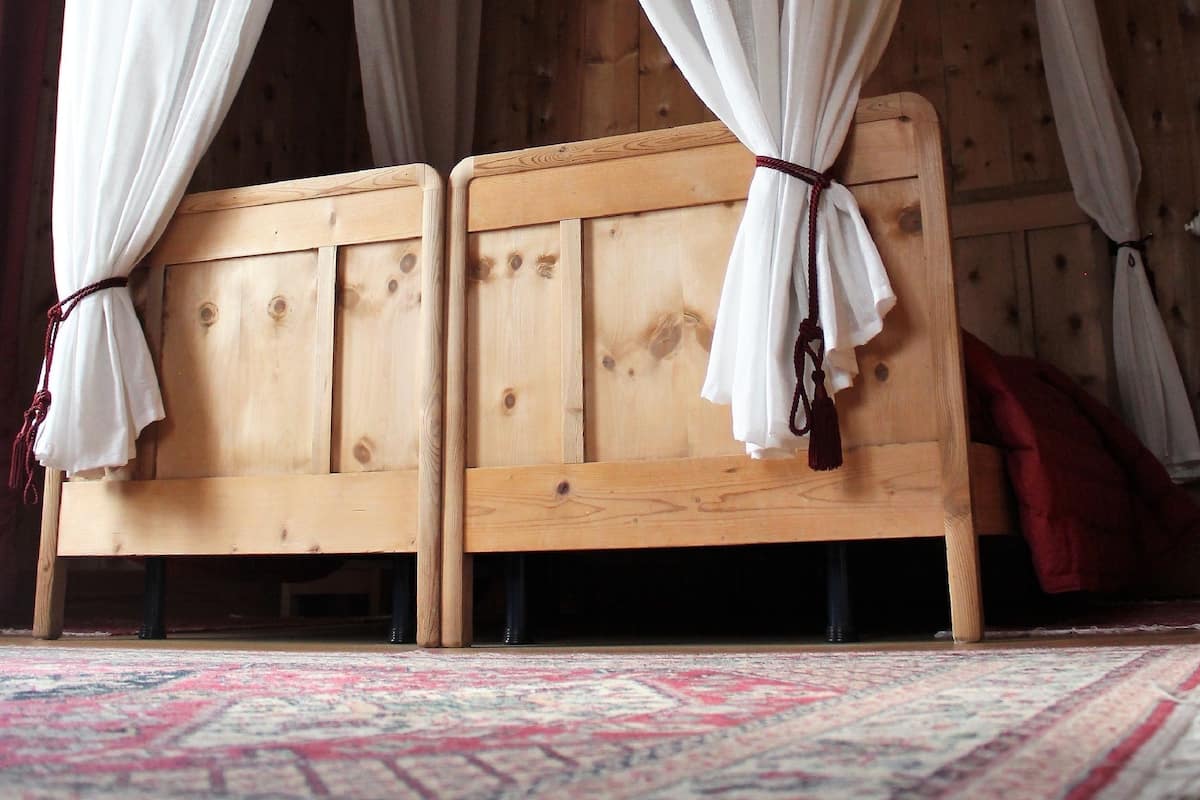 A wooden bed with a canopy, a patterned rug, and wooden walls.