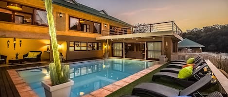 Een buitenzwembad, ligstoelen bij het zwembad