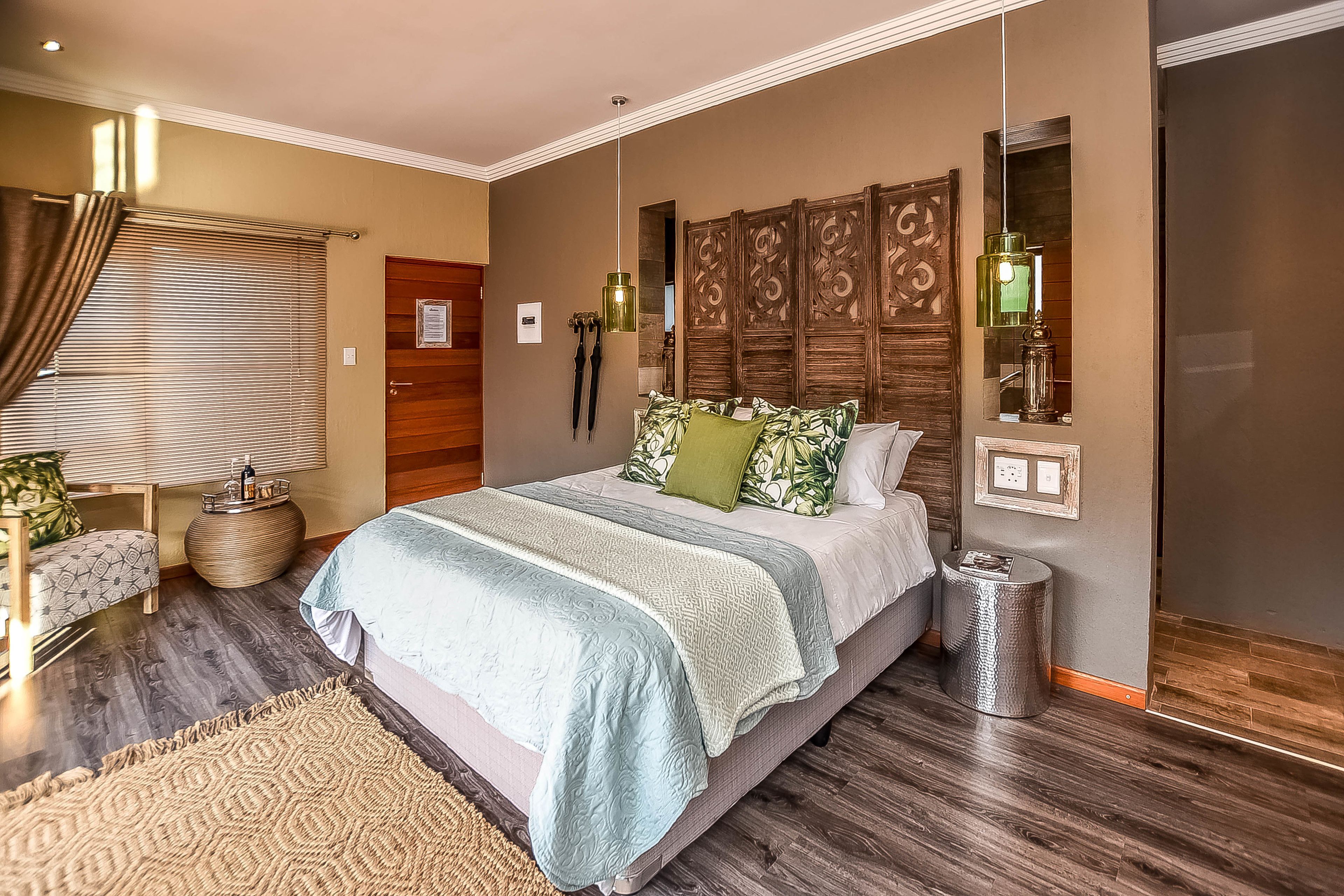 Quarto com uma cama grande, cabeceira de madeira, mesa de cabeceira, abajur e espelho.