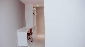 A modern, minimalistic room with a white desk, a red chair, and a white wardrobe. - Rede Andrade Lapa (Rio de Janeiro)