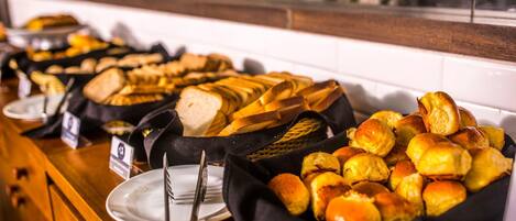 A buffet with various breads and pastries.