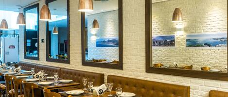 Un restaurante con mesas de madera largas, asientos de cuero marrón y lámparas colgantes.