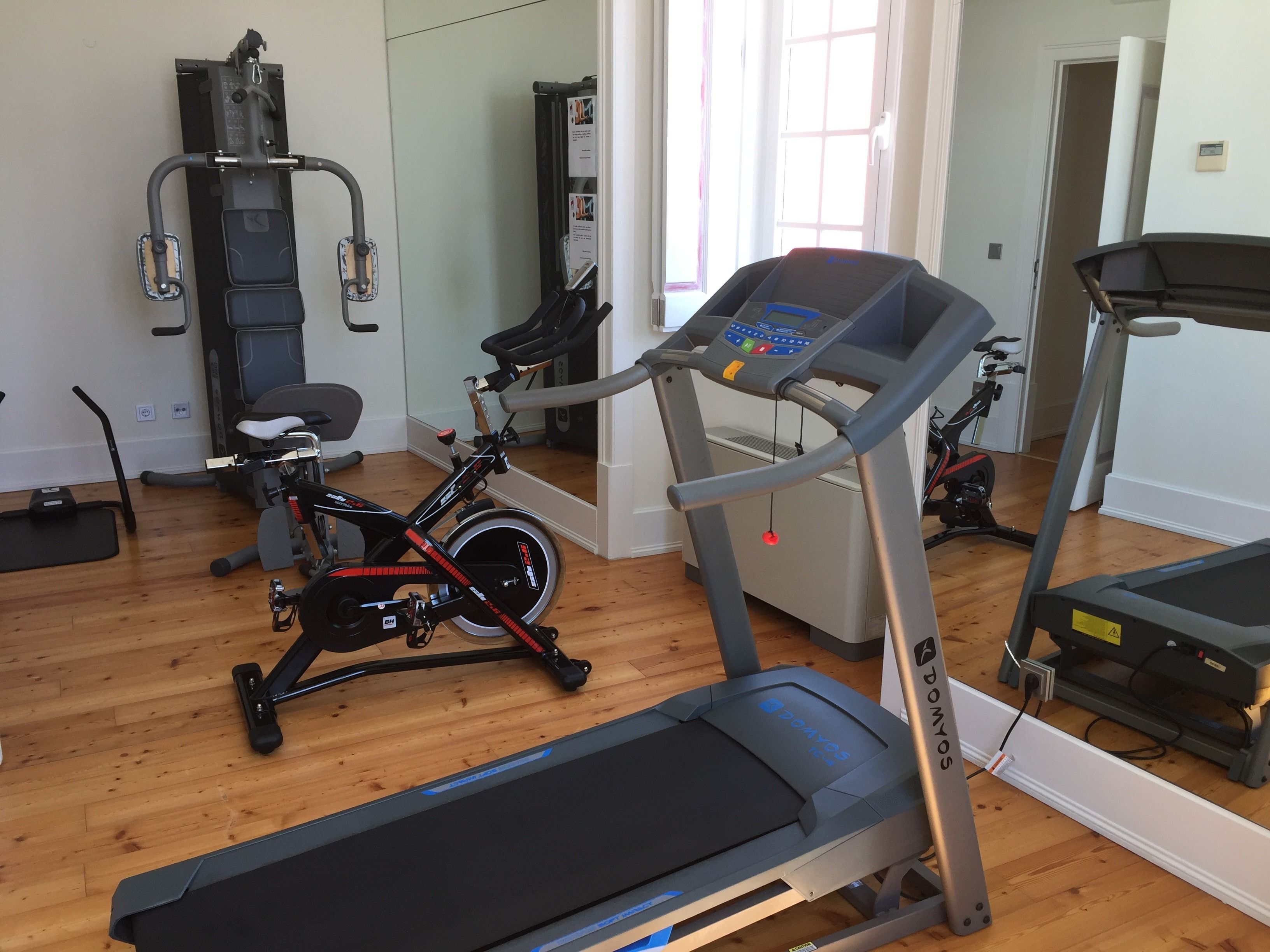 A home gym with a treadmill, stationary bike, and elliptical machine.